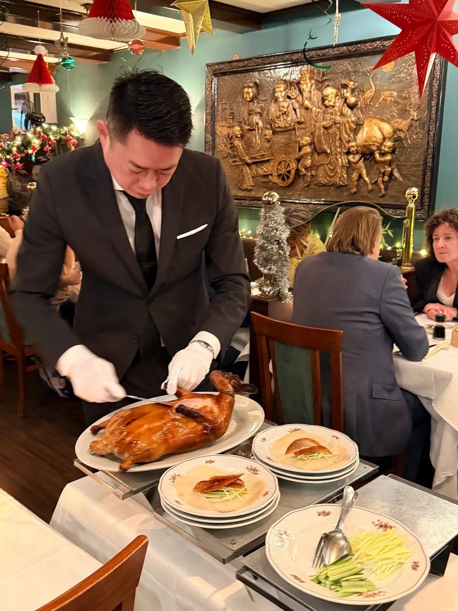 Een ober snijdt de krokante Peking eend aan tafel aan