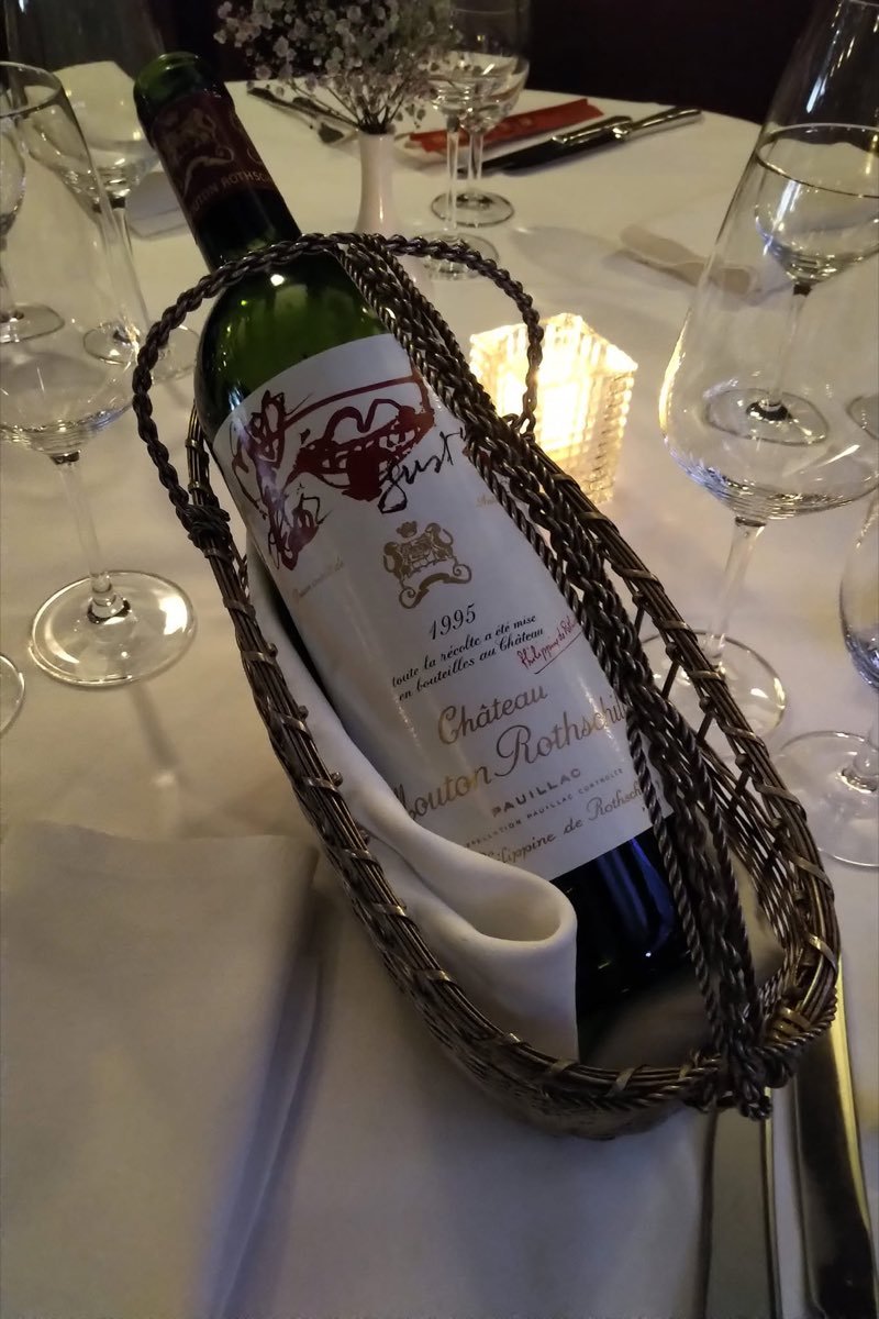 Fles Château Mouton Rothschild in een mandje op tafel